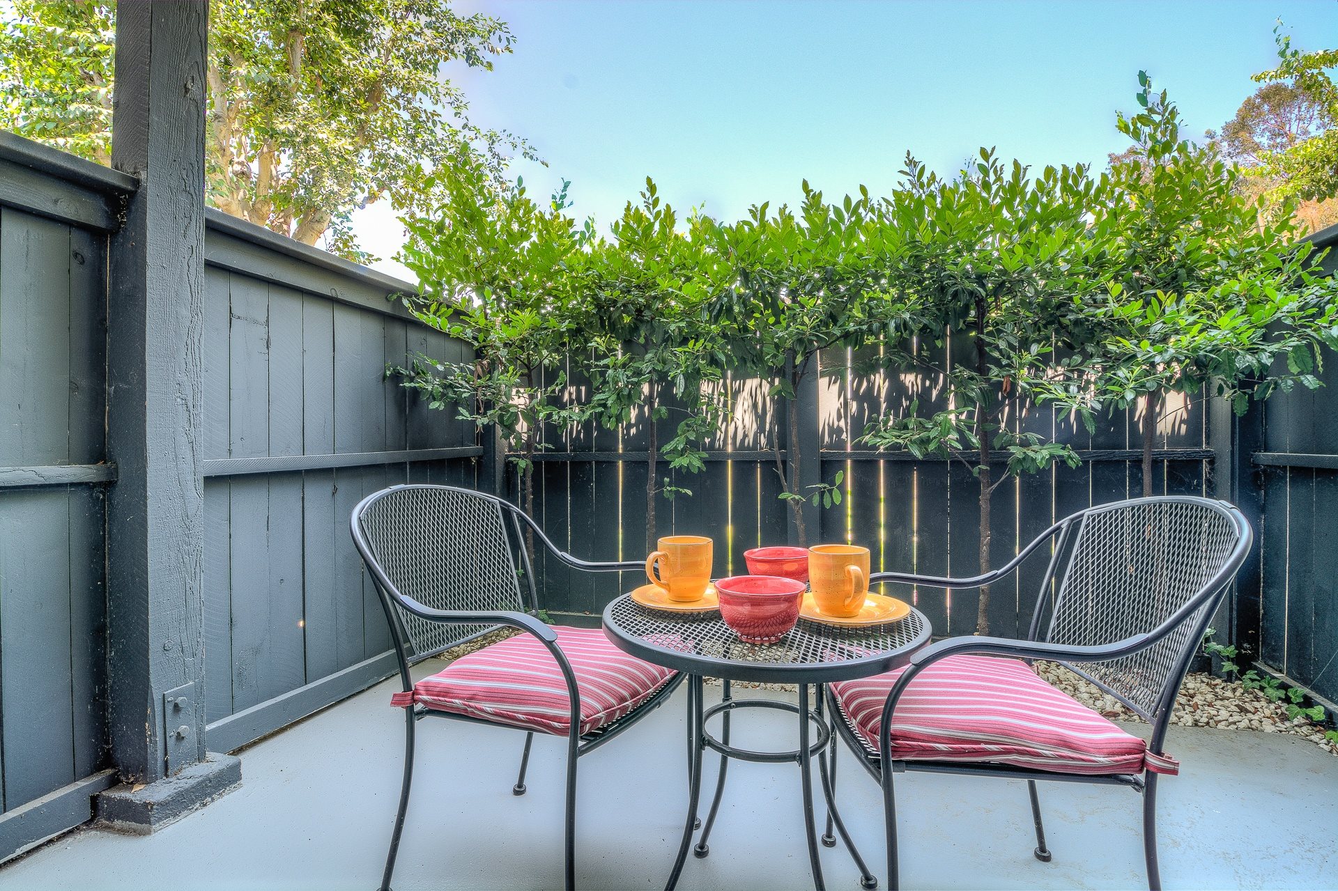 A patio with a table and chairs and a fence.,A patio with a table and chairs and a fence.